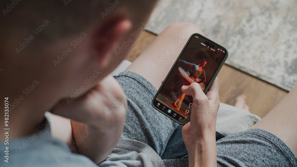 Poster teen boy scrolls through and watches social network feed with short videos using mobile phone while 
