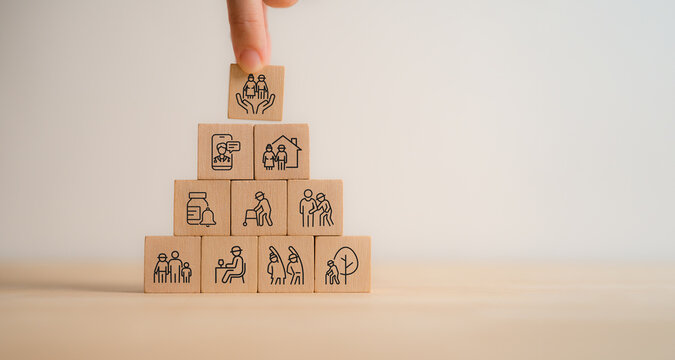 Elderly care concept. Hand holds wooden cubes with icons related to elderly care, medical, rehabilitation service, nursing care for enhancing quality of life in elder people. Used banner, brochure.