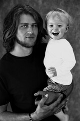 a man holding a baby and smiling with a shirt that says  baby  on it.