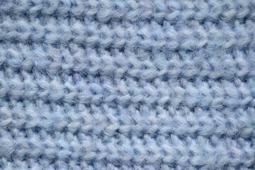 macro texture of woolen blue crocheted sweater as background, close-up of blue crocheted front surface, woolen texture of woolen wool, knitted front surface