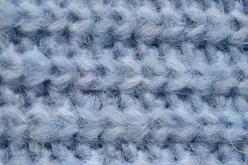 macro texture of woolen blue crocheted sweater as background, close-up of blue crocheted front surface, woolen texture of woolen wool, knitted front surface