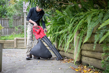 Man working with a leaf vacuum in the backyard. Auckland.