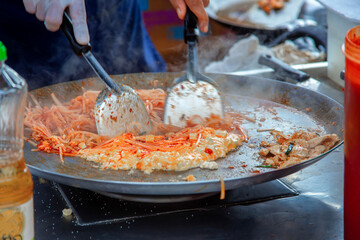 Cooking street food in Thailand. A traditional Thai dish called pad thai. Fried rice noodles in a pan. Asian pad thai noodle cooking process on the streets of Thailand