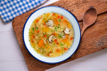 Short noodle soup with vegetables and mushrooms. Top view table with  decoration.