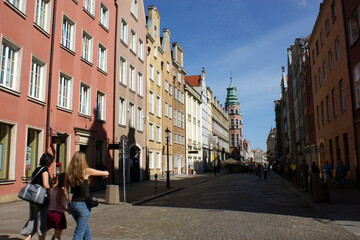 Old town square buildings lit by the sun in a row, people in the market square Poland Gdańsk