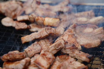 Close-up of pork belly being grilled on a charcoal grill.
