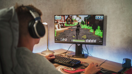Caucasian teenager wearing headphones plays online video game on PC, spends leisure time at home....