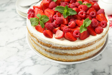 Tasty sponge cake with fresh berries and mint on white marble table, closeup