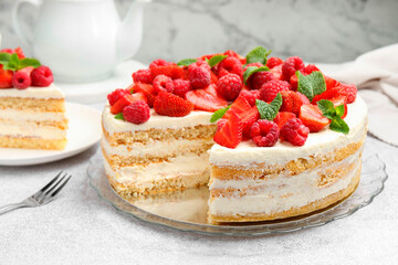 Tasty sponge cake with fresh berries and mint on light gray table, closeup