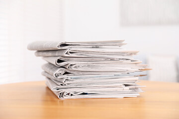 Stack of many newspapers on wooden table
