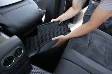 Man taking grey rubber car mat from auto, closeup