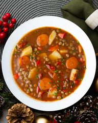 Spicy stewed lentils with vegetables and potatoes. Top view table with Christmas decoration.