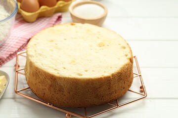 Tasty sponge cake and ingredients on white wooden table