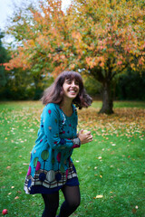 a girl in a dress with balloons is playing in the autumn garden