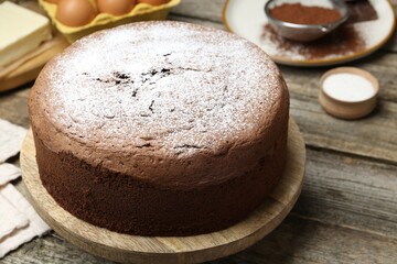 Tasty chocolate sponge cake with powdered sugar on wooden table