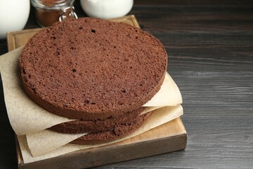 Cut chocolate sponge cake and ingredients on wooden table, closeup