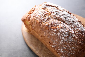 Tasty sponge cake with powdered sugar on grey table, closeup