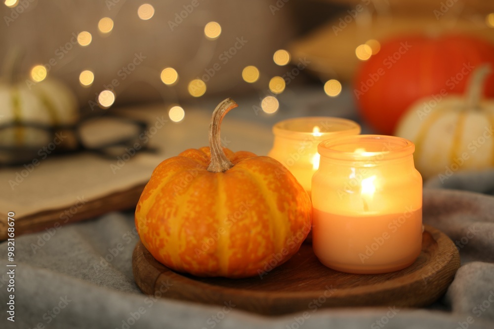 Canvas Prints Burning candles and pumpkin on grey cloth against blurred lights, closeup. Autumn atmosphere