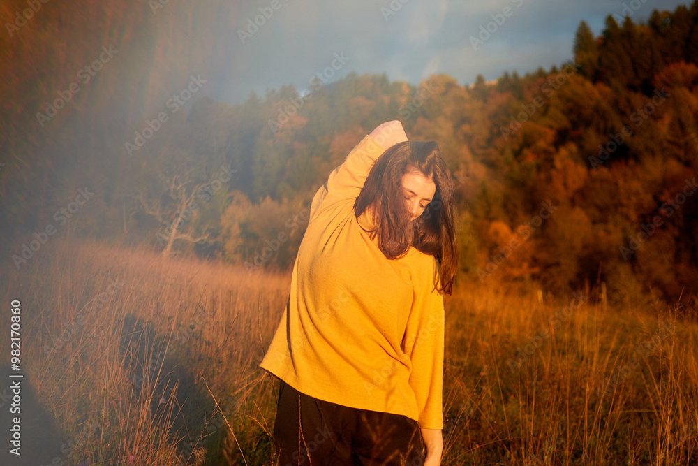 Wall mural a portrait young woman in mustard sweater in autumn mountains at sunset