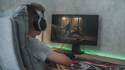 Caucasian teenager in headphones watches action movie with fight online on personal computer while...