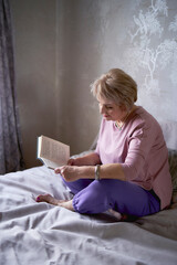 elderly woman reads a book at home