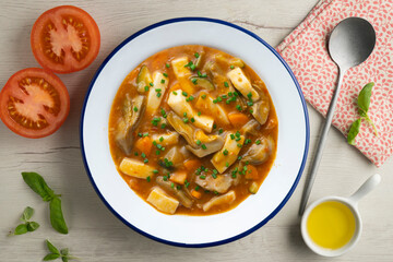 Squid stew with potatoes, artichokes and vegetables. Top view table with  decoration.