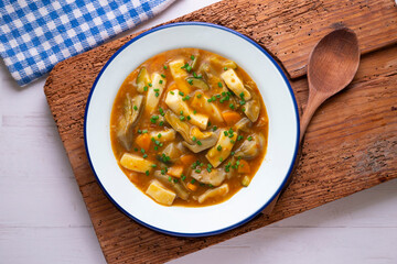 Squid stew with potatoes, artichokes and vegetables. Top view table with  decoration.
