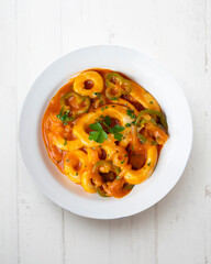 Squid stew with potatoes, artichokes and vegetables. Top view table with  decoration.