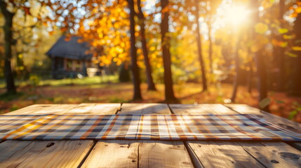 Empty wooden table with tablecloth ready for picnic or barbeque  at the autumn nature. Trees with yellow leaves at the background