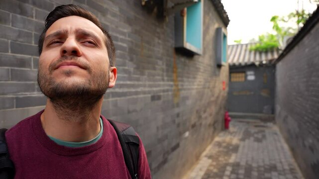 Man exploring traditional Siheyuan houses at Jiuwan Hutong in Beijing, China. Close up, handheld