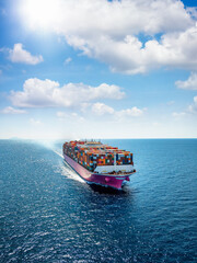 Aerial vertical front view of a heavy loaded container carrier ship sailing with speed over the...