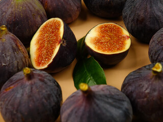    Whole fruits and two halves of ripe purple figs lie on a pink plate  