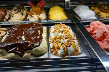 A colorful display of various gelato flavors in a dessert shop. Ideal for food-related projects, restaurant advertisements, or culinary blogs focused on sweets and indulgence.