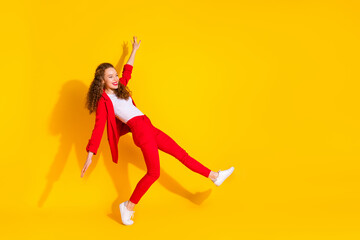 Full size photo of pretty young woman dance chill empty space wear red suit isolated on yellow color background