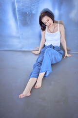 young teenage girl fighting brain cancer at photo shoot in studio sitting on floor, leaning against...