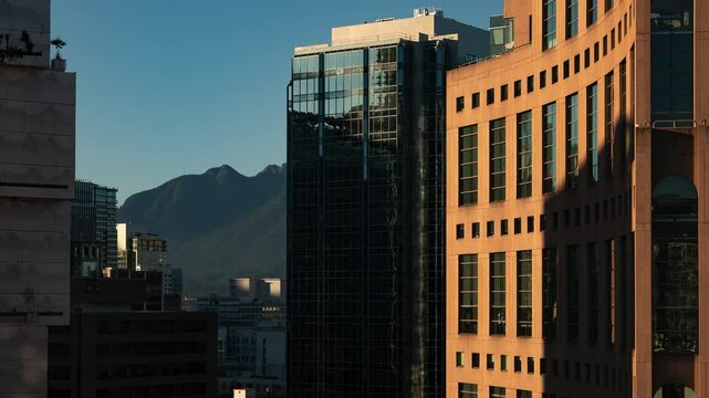 Close up timelapse showing the su set in the Vancouver as the shadows cast on the public library move through the day with an orange glow and contrast with mountains in the background