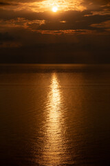 Fototapeta premium Golden sunset reflecting on calm ocean water with dramatic clouds