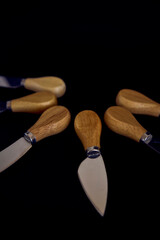 a set of fish and cheese knives with a wooden handle on a black background
