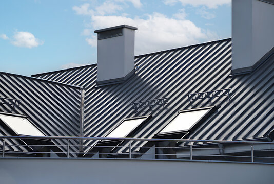 Close-up house retro roof panel with standing seam and fasteners. Modern galvanized steel roofing sheet with ribs. Classic style black metal panel with rebate joint. Falz roofing. Building's covering
