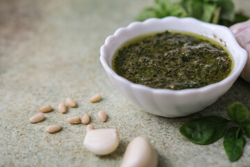 Close-up of bowl of fresh pesto sauce with ingredients, copy space