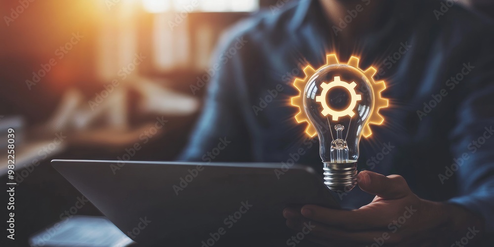 Aufkleber A man holds a light bulb with a gear icon inside while using a notebook computer, representing the inspiration for innovative ideas through online technology.