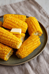 Homemade Organic Steamed Yellow Sweet Corn on the Cob with Butter, side view.