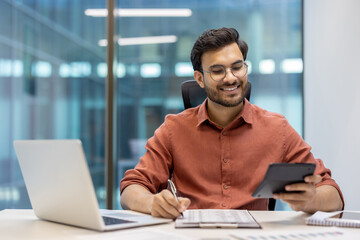 Successful happy financier behind paper work inside office, businessman smiling prepares financial...