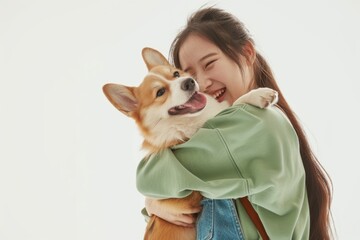 Obraz premium A woman is hugging a dog with a smile on her face. The dog is a corgi and he is happy and content. The woman seems to be enjoying the moment and the company of her pet