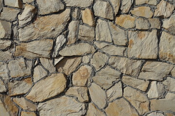 Rough surface of wall made of beige natural shape fieldstones