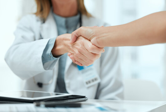 Consulting, doctor and handshake with people in hospital office for medical agreement or meeting. Deal, interview or partnership with healthcare professional and patient shaking hands in clinic