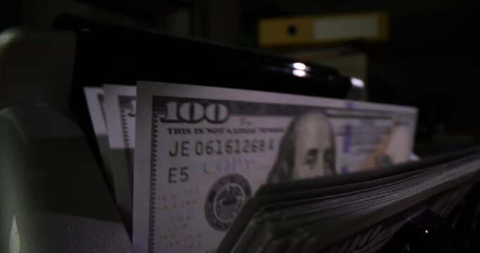 Closeup of bank machine for counting cash on dark background. One hundred dollar bills currency exchange and machine counts money