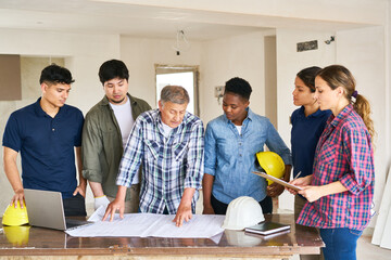 Team of construction workers and senior architect discussing over blueprint design in meeting at...