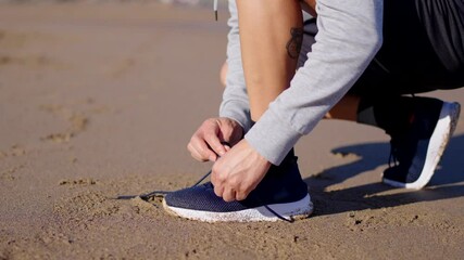 Closeup of athlete tying shoe laces at the beach.