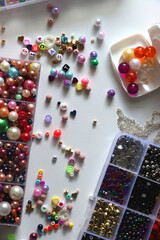 Colorful beads, letter beads, threads and other jewelry making supplies on white background. Making friendship bracelets concept. Flat lay.